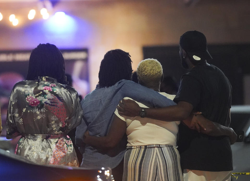 Onlookers comfort each other as they stand outside the police tape while Houston Police investigate a fatal shooting at DD Sky Club in Houston on Tuesday, Oct. 20, 2020. (Elizabeth Conley/Houston Chronicle via AP)