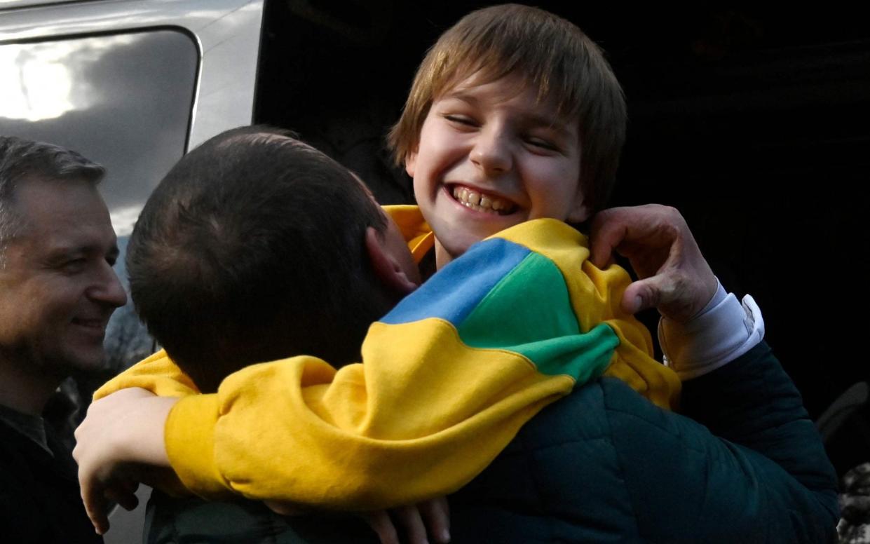 Denys Zaporozhchenko saw his children Nikita, Yana and Dayana for the first time in months after meeting their bus from Crimea in Kyiv - SERGEI CHUZAVKOV/AFP