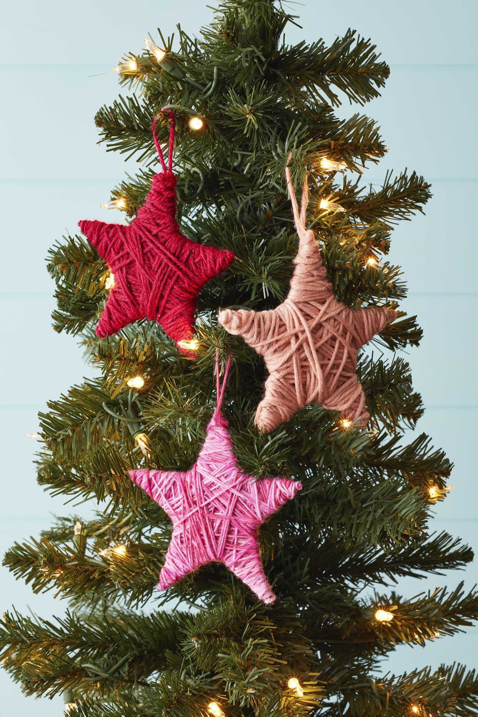 star shaped ornaments covered in colorful yarn hung on a christmas tree