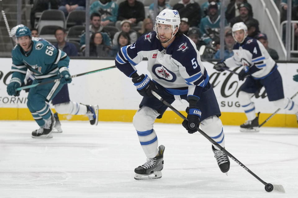 Winnipeg Jets defenseman Brenden Dillon (5) looks to pass the puck against the San Jose Sharks during the first period of an NHL hockey game in San Jose, Calif., Thursday, Jan. 4, 2024. (AP Photo/Jeff Chiu)