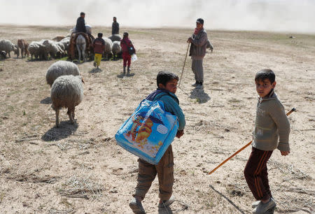 A boy carries his belongings as he escapes fight between Iraqi forces and Islamic State fighters south of Mosul, Iraq February 24, 2017. REUTERS/Goran Tomasevic