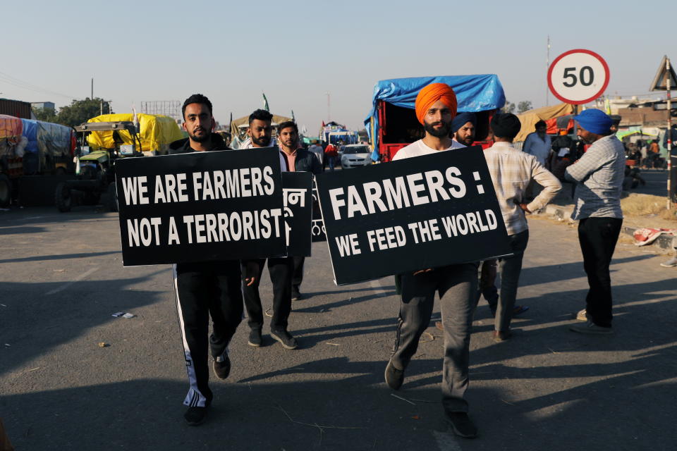 Dos manifestantes portan carteles en los que se leen: “Somos agricultores, no terroristas” y “Agricultores: nosotros alimentamos al mundo”. (Foto: Anushree Fadnavis / Reuters).