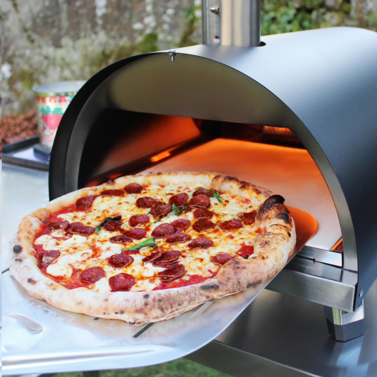  pepperoni pizza being taken out of a Woody pizza oven 