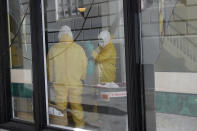 Men in hazardous material suits work inside the Abigail Hotel in San Francisco, Thursday, April 2, 2020. The hotel is one of several private hotels San Francisco has contracted with to take vulnerable people who show symptoms or are awaiting test results for the coronavirus. (AP Photo/Jeff Chiu)