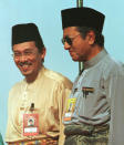 FILE - In this June 20, 1998, file photo, Anwar Ibrahim, left, stand next to Malaysia Prima Minister Mahathir Mohamad during the 1998 UMNO Annual Meeting in Kuala Lumpur. Political tension is building in Malaysia amid talks that Mahathir will pull his party out of the ruling alliance and team up with opposition parties to form a new government in a major political upheaval. It will thwart his named successor Anwar Ibrahim from taking over.(AP Photo/Vincent Thian, File)