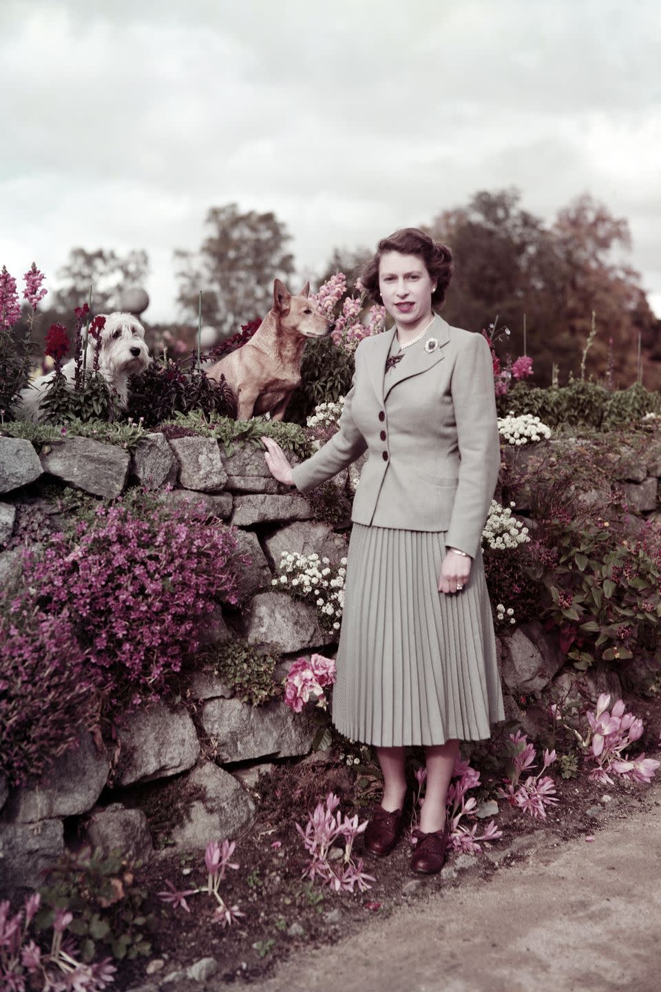 <p>Queen Elizabeth II with two dogs on the grounds at Balmoral Castle in Scotland.</p>