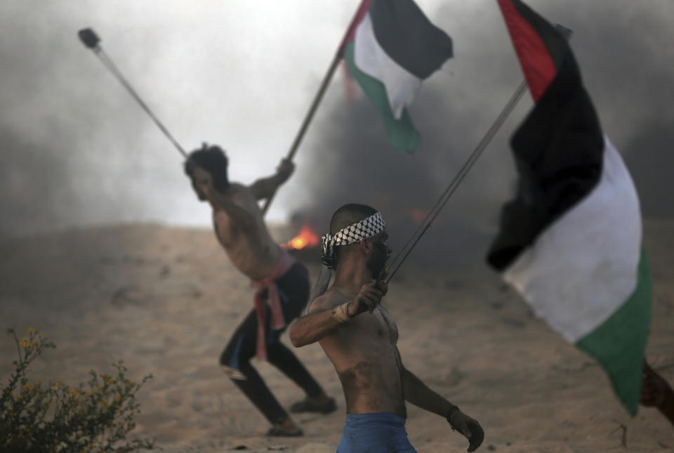 Palestinian protesters hurl stones at Israeli troops during a protest on the beach at the border with Israel near Beit Lahiya, northern Gaza Strip, Monday, Oct. 22, 2018. (AP Photo/Khalil Hamra)