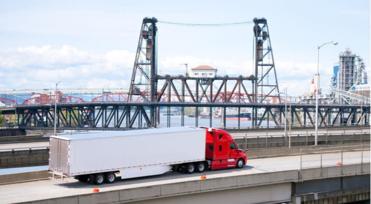 a red and white truck travelling down a highway during daylight