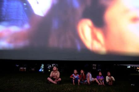 Children sit in a soccer field watching films, during a wedding party in Tangerang, Indonesia, April 15, 2017. REUTERS/Beawiharta/Files