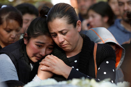 Alicia Moreno, wife of late Cesar Jimenez Brito, 40, who died during the explosion of a fuel pipeline ruptured by oil thieves, holds hands with her daughter during his funeral service at the cemetery in the municipality of Tlahuelilpan, state of Hidalgo, Mexico January 20, 2019. REUTERS/Henry Romero