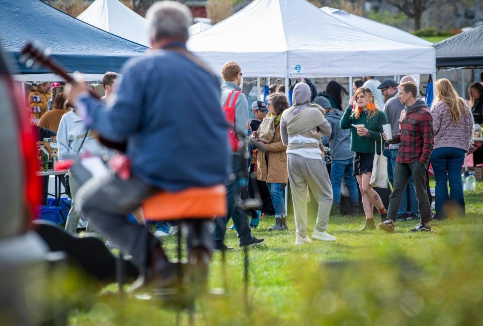 As Tom Harlan plays music, Customers walk through the Woolery Farmers' Market on Saturday, April 8, 2023.