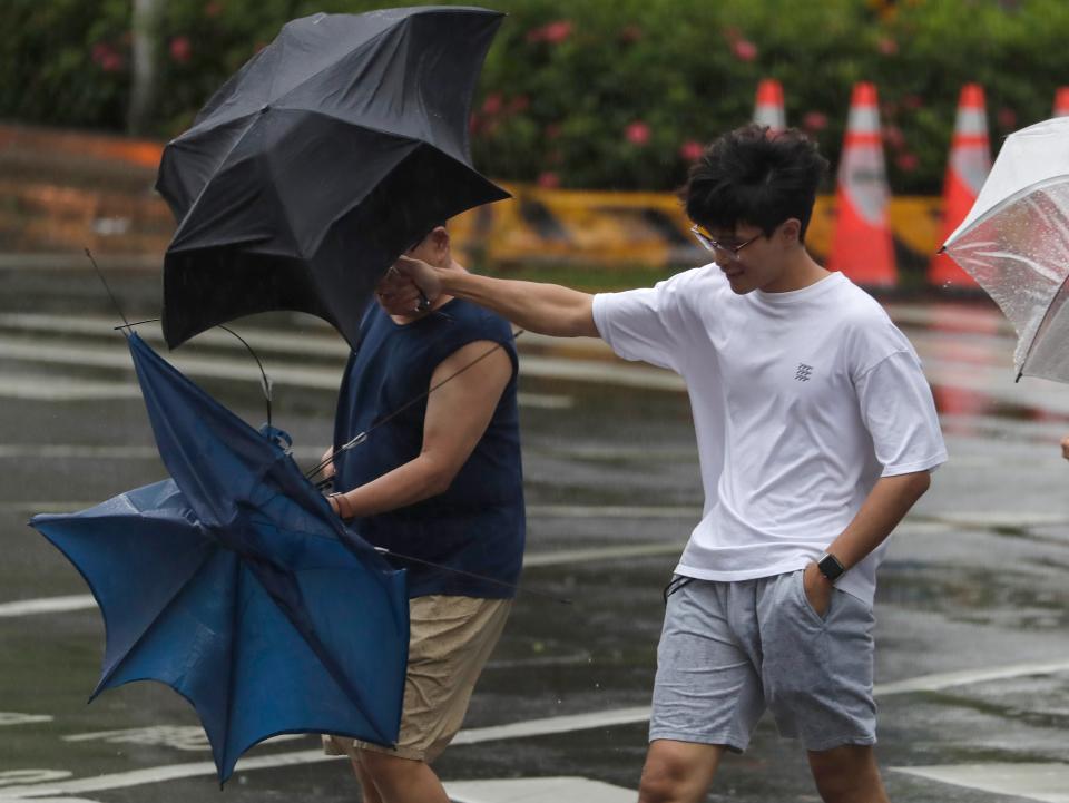 Two men struggle with their umbrellas against gusts of wind generated by Typhoon Gaemi in Taipei, Taiwan (AP)