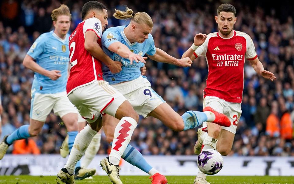 Manchester City's Erling Haaland, center right, duels for the ball with Arsenal's William Saliba during the English Premier League soccer match between Manchester City and Arsenal at the Etihad