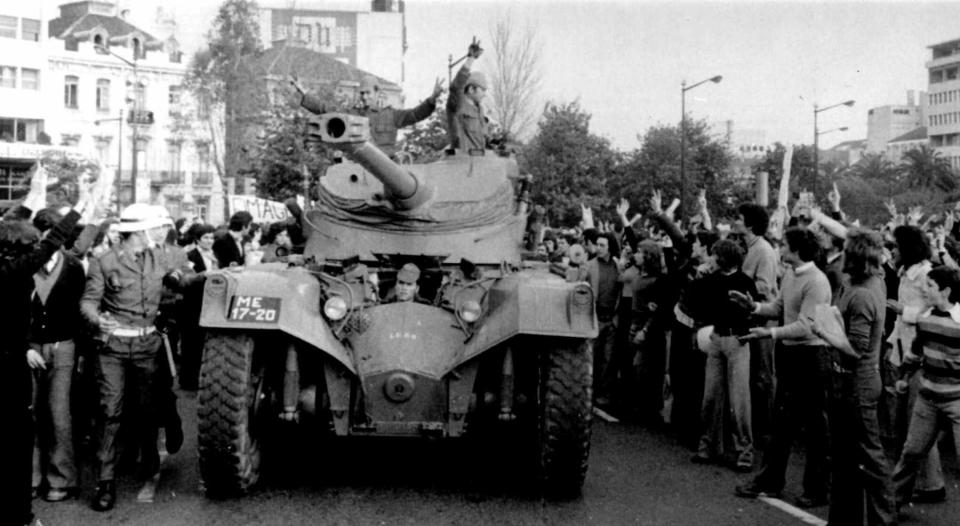 FILE - In this April 25 1974 file picture, people cheer soldiers in a tank driving through downtown Lisbon during a military coup. Euphoria gripped Portugal during the 1974 Carnation Revolution, when junior army officers swept away a four-decade dictatorship. The almost bloodless coup brought what for the Portuguese were novelties _ the right to vote, universal health care, public education, old-age pensions and labor rights. (AP Photo/Antonio Aguiar)