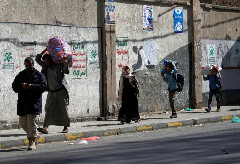 Yemenis carry their belongings as they flee an area in the Yemeni capital Sanaa on December 3, 2017, during clashes between Huthi rebels and supporters of Yemen's ex-president Ali Abdullah Saleh