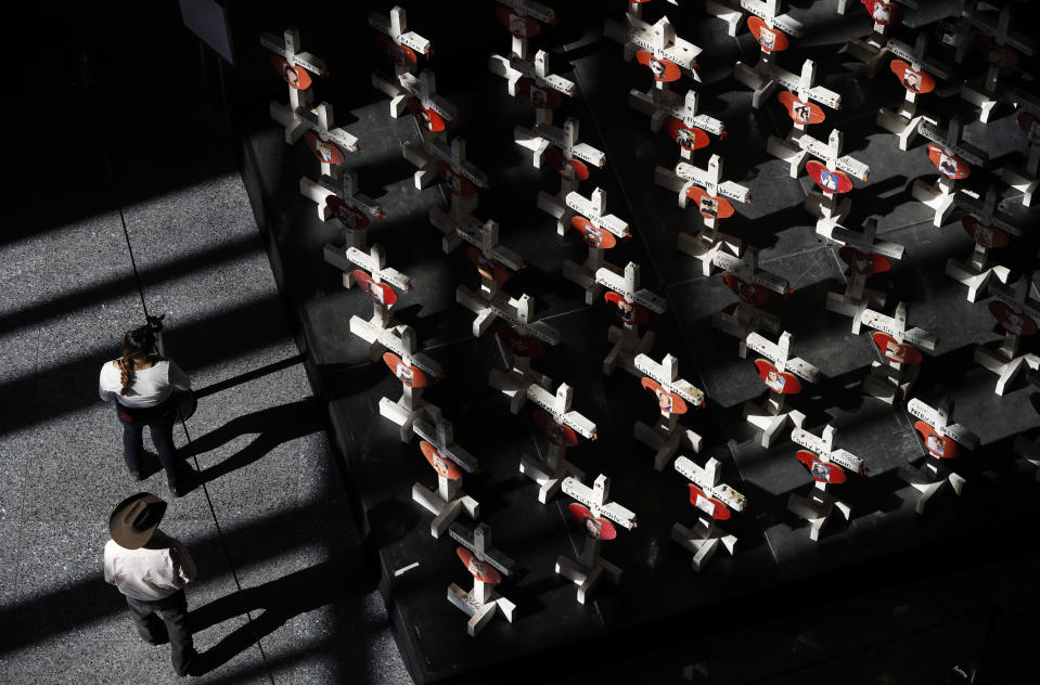 In this Sept. 25, 2018, photo, people look at a display of wooden crosses and a Star of David on display at the Clark County Government Center in Las Vegas. The crosses and Star of David had been part of a makeshift memorial along the Las Vegas Strip erected in memory of the victims of the Oct. 1, 2017, mass shooting in Las Vegas. (AP Photo/John Locher)