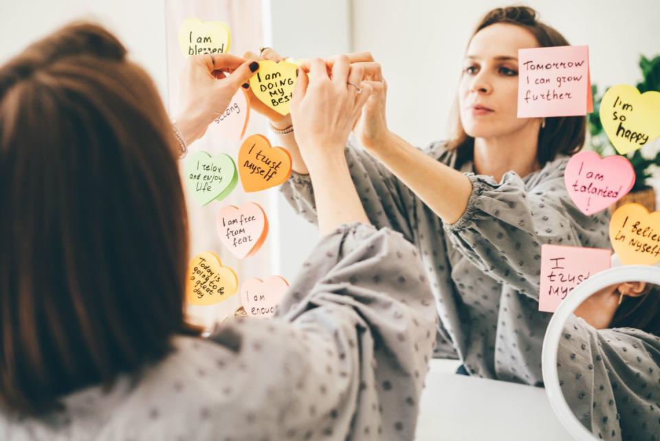 woman stick a sticker with affirmations on the mirror