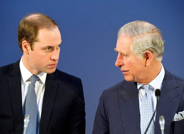 William and Charles look towards one another as they sit together at a conference