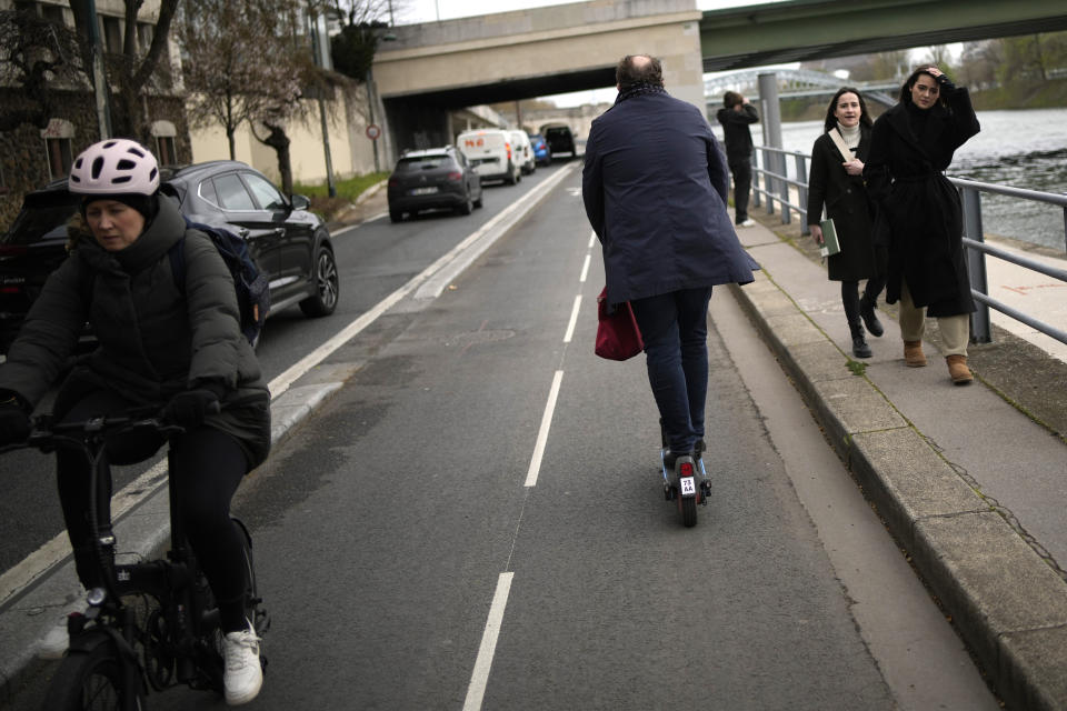 A man rides a scooter near the Seine river banks in Paris, Friday, march 31, 2023. Romantically zipping two-to-a-scooter, wind in the hair, past the Eiffel Tower and other iconic sights could soon become a thing of the past if Parisians vote Sunday to do away with the 15,000 opinion-dividing micro-machines. (AP Photo/Christophe Ena)