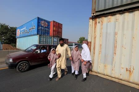 A man with his children walk past containers, which will be used to block roads during a planned protest called by political party Pakistan Tehreek-e-Insaf (PTI) in Islamabad, Pakistan, October 31, 2016. REUTERS/Faisal Mahmood