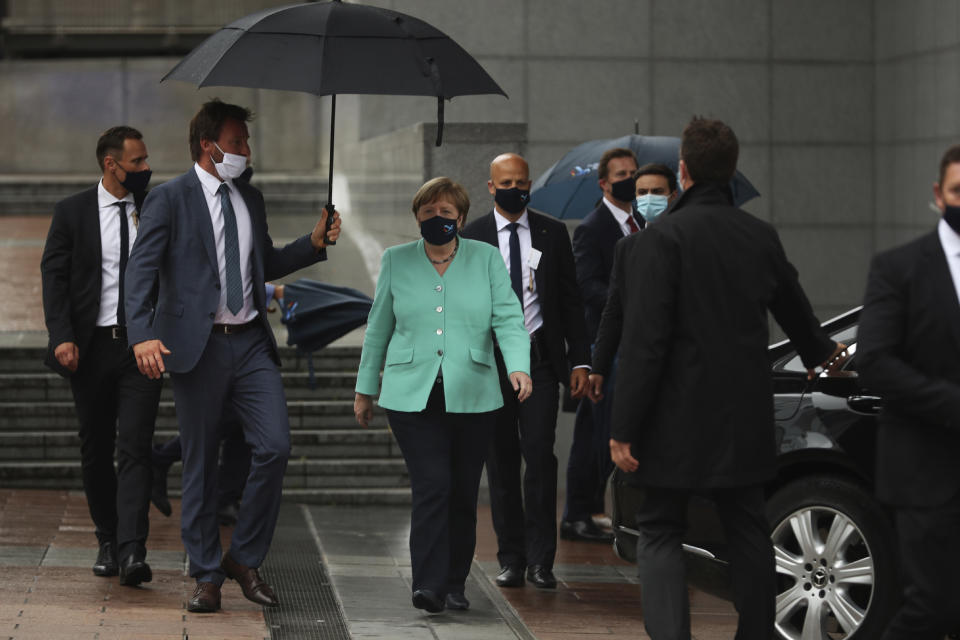 FILE- In this Wednesday, July 8, 2020 file photo, German Chancellor Angela Merkel, center, walks under an umbrella as she leaves, after addressing a plenary session, at the European Parliament in Brussels. European Union leaders will meet face-to-face on Friday, July 17, 2020 for their summit as they try to carve up a potential package of 1.85 trillion euros among themselves. In perhaps the first such major meeting of leaders since the COVID-19 outbreak hit the world, the stakes were just too high for attendees not to look one another in the eye. (AP Photo/Francisco Seco, File)