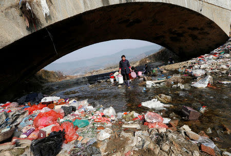 Villagers wash clothes in the garbage-filled Shenling River, in Yuexi county, Anhui province, China February 14, 2015. REUTERS/William Hong/File Photo