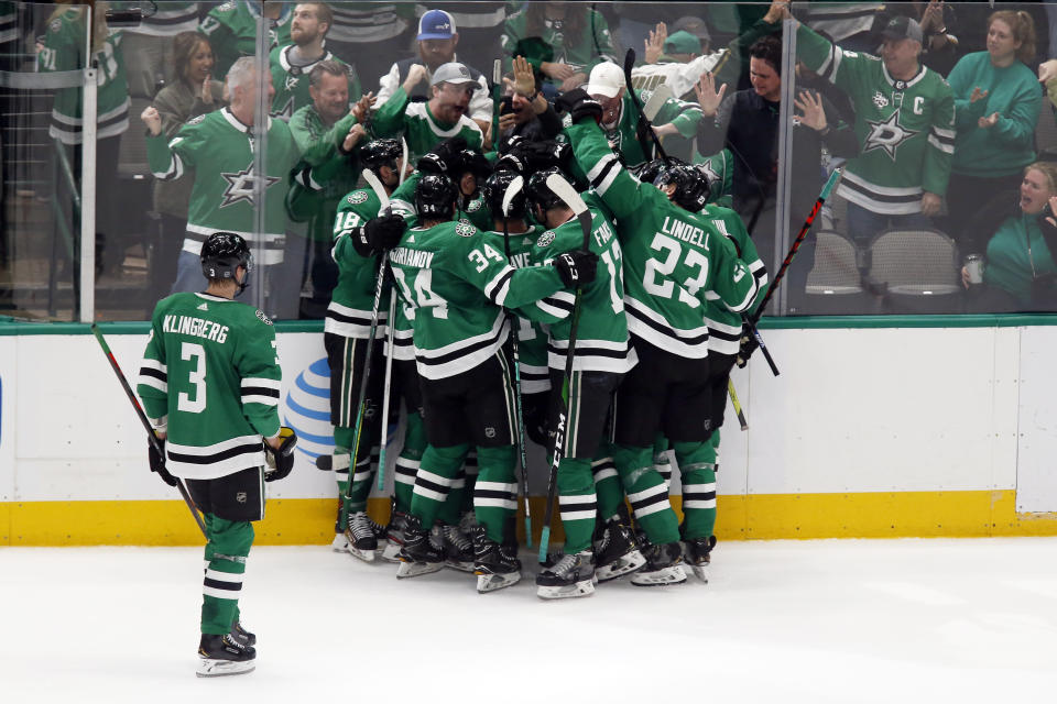 Dallas Stars left wing Jamie Benn, obscured, is mobbed by teammates as they celebrate a 3-2 overtime win against the Tampa Bay Lightning during an NHL hockey game in Dallas, Monday, Jan. 27, 2020. (AP Photo/Ray Carlin)