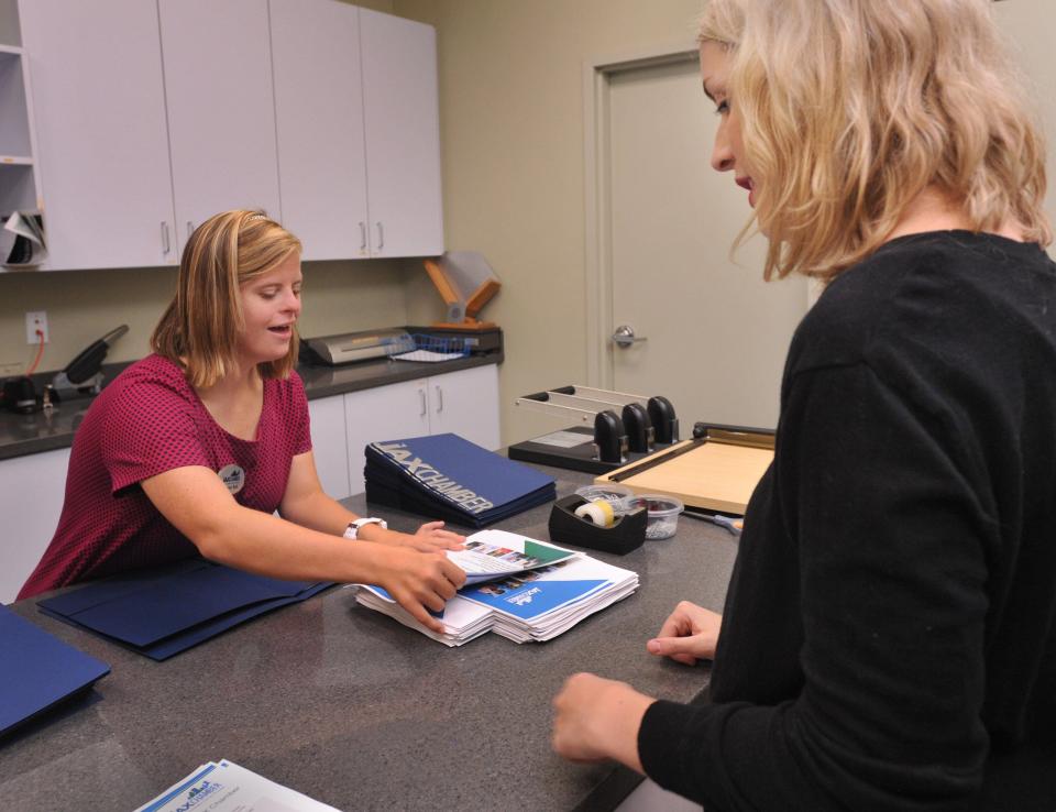 Megan Bell (left), who has Down syndrome, puts packets together with Sarah Mills at the JAX Chamber in 2018. Bell works there three days a week.