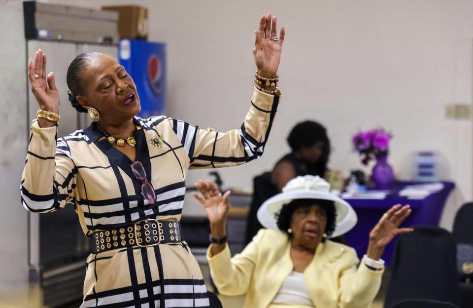 Bertha Gober, left, a devoted member of St. John Institutional Missionary Baptist Church, raises her hands in worship during a recent Sunday morning service inside the church’s temporary location in its fellowship hall, July 23, 2023, in Miami’s historic Overtown neighborhood.