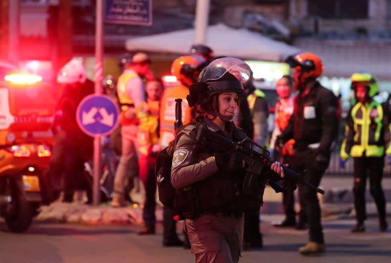 Police officers and medics stand near a body, near Damascus Gate