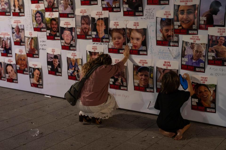 A woman touches photos of Israelis missing and held captive in Gaza, displayed on a wall in Tel Aviv (AP)