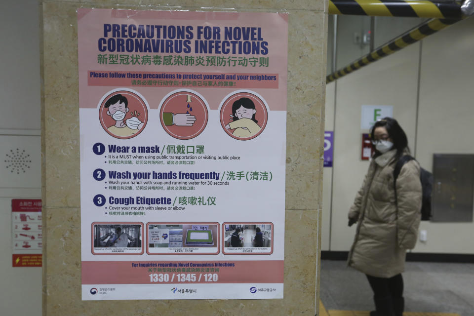 A woman passes by a poster about precautions against a new coronavirus at a subway station in Seoul, South Korea, Thursday, Feb. 6, 2020. Ten more people were sickened with a new virus aboard one of two quarantined cruise ships with some 5,400 passengers and crew aboard, health officials in Japan said Thursday, as China reported 73 more deaths and the World Health Organization appealed for more funds to help countries battle the spread of the disease. (AP Photo/Ahn Young-joon)