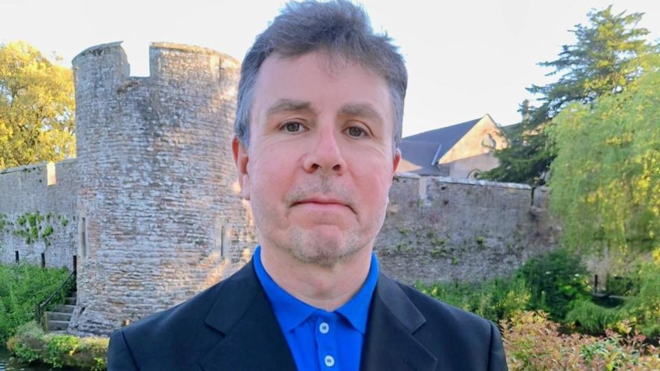 Peter Welsh standing in front of a stone castle-shaped structure.