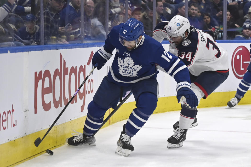 Toronto Maple Leafs left winger Zach Aston-Reese (12) battles for the puck against Columbus Blue Jackets center Cole Sillinger (34) during second-period NHL hockey game action Saturday, Feb. 11, 2023, in Toronto. (Jon Blacker/The Canadian Press via AP)