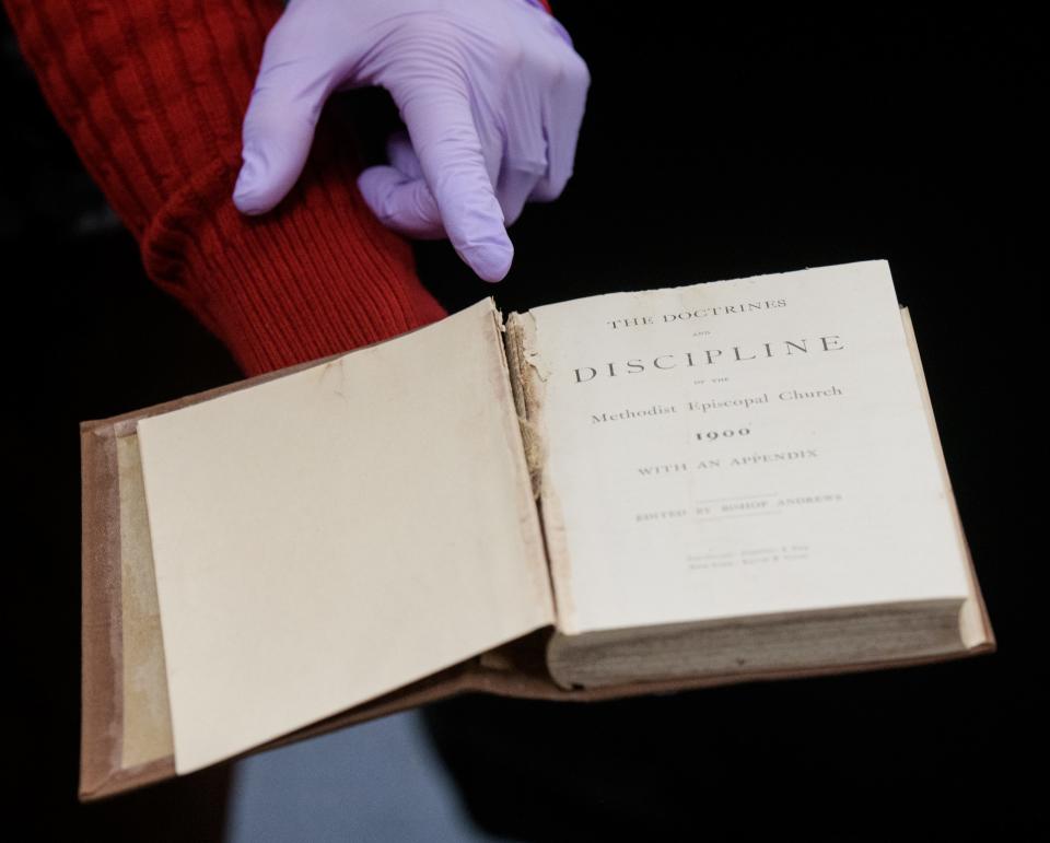 Paper conservator Ana Lyra points out some damage to the spine of a well-preserved copy of The Doctrines and Discipline of the Methodist Episcopal Church from 1900 discovered in the Hale Memorial Church time capsule.