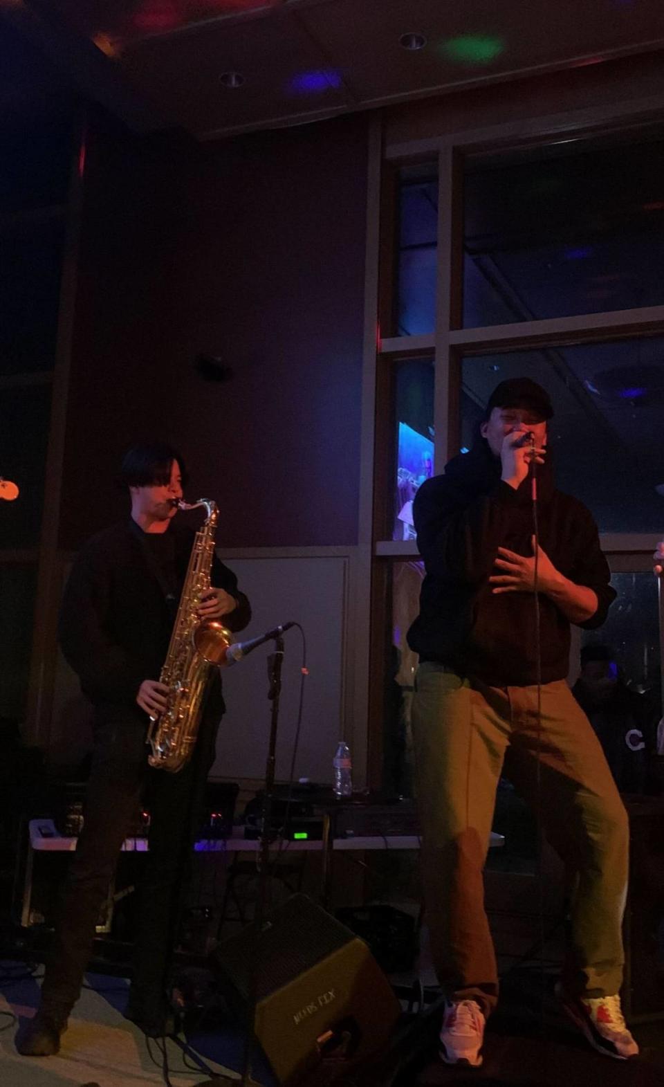 Vocalist Nobi (right) stands on speakers just off stage while his band, the Force, plays behind him. Tenor saxophonist Weijun Huang (left) plays directly behind Nobi, a Tri-Cities native.