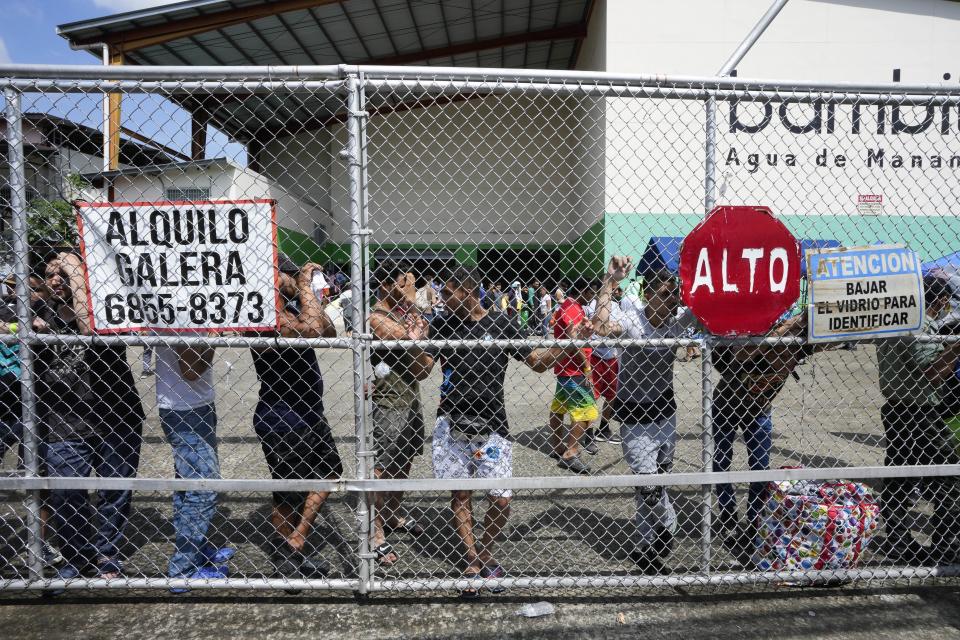 Venezuelan migrants hoping to return to their country of origin, wait to be driven to the international airport, outside a commercial warehouse being used as a temporary shelter, in Panama City, Wednesday, Oct. 26, 2022. (AP Photo/Arnulfo Franco)