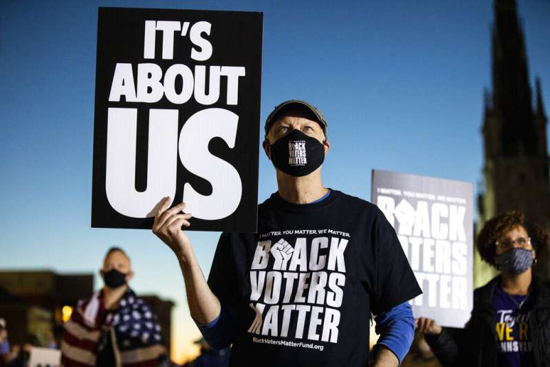 賓州哈里斯堡一名抗議者4日在街頭舉牌，抗議川普要求停止計票的說法。手上的牌子寫著「此事關乎美國」。（美聯社）