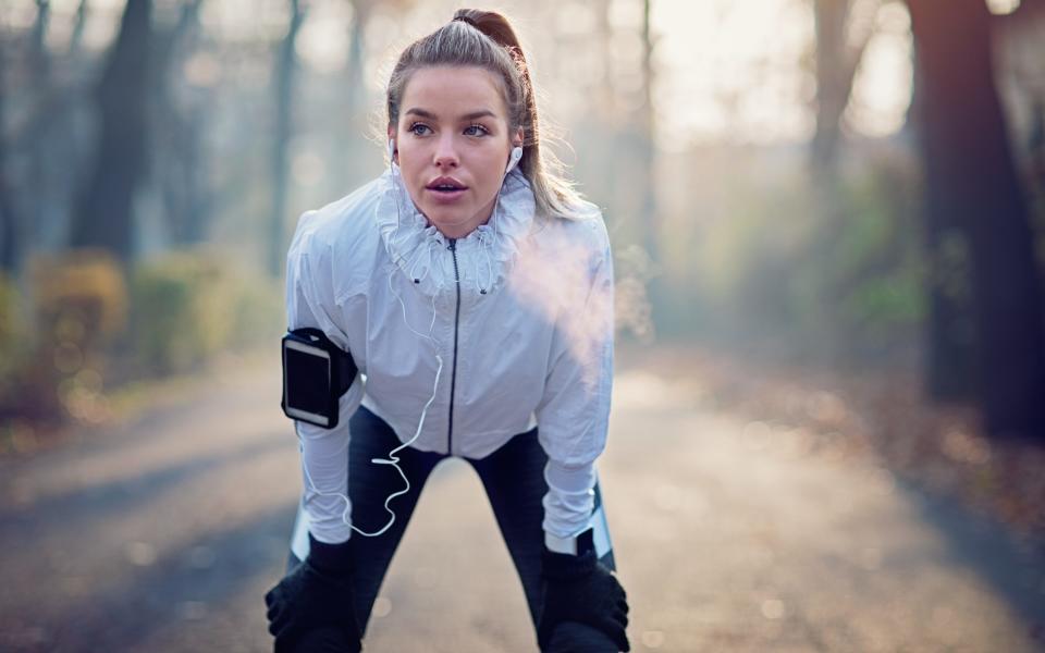 Young girl is resting exhausted after run in foggy morning