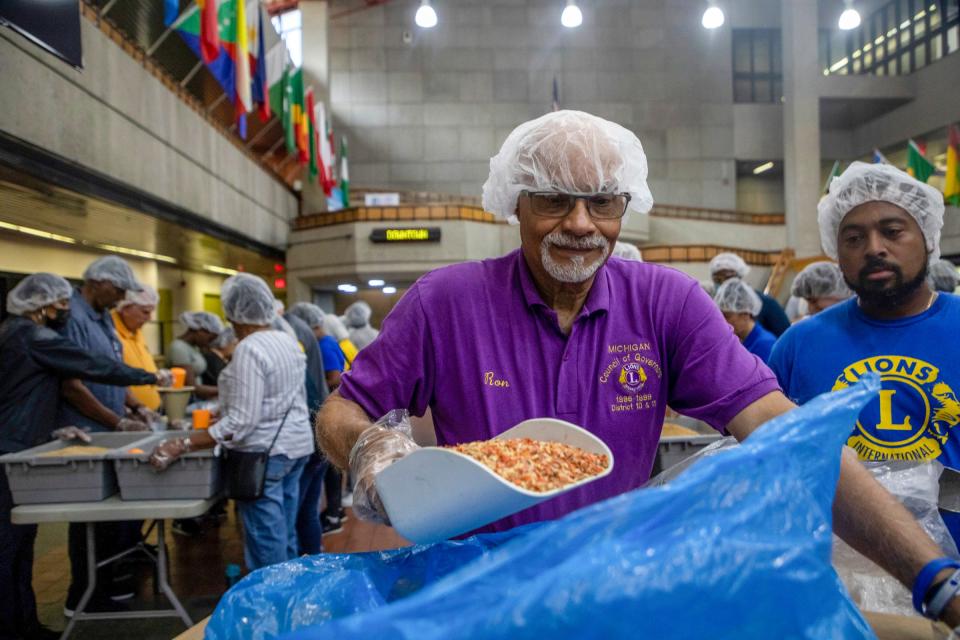 Ron Coleman, 80, a past district governor for the Lions Club International, holds a big scoop full of dehydrated veggies as he stands next to Andrew Whidby Jr. inside the Wayne County Community College in Detroit on Saturday, June 10, 2023. 