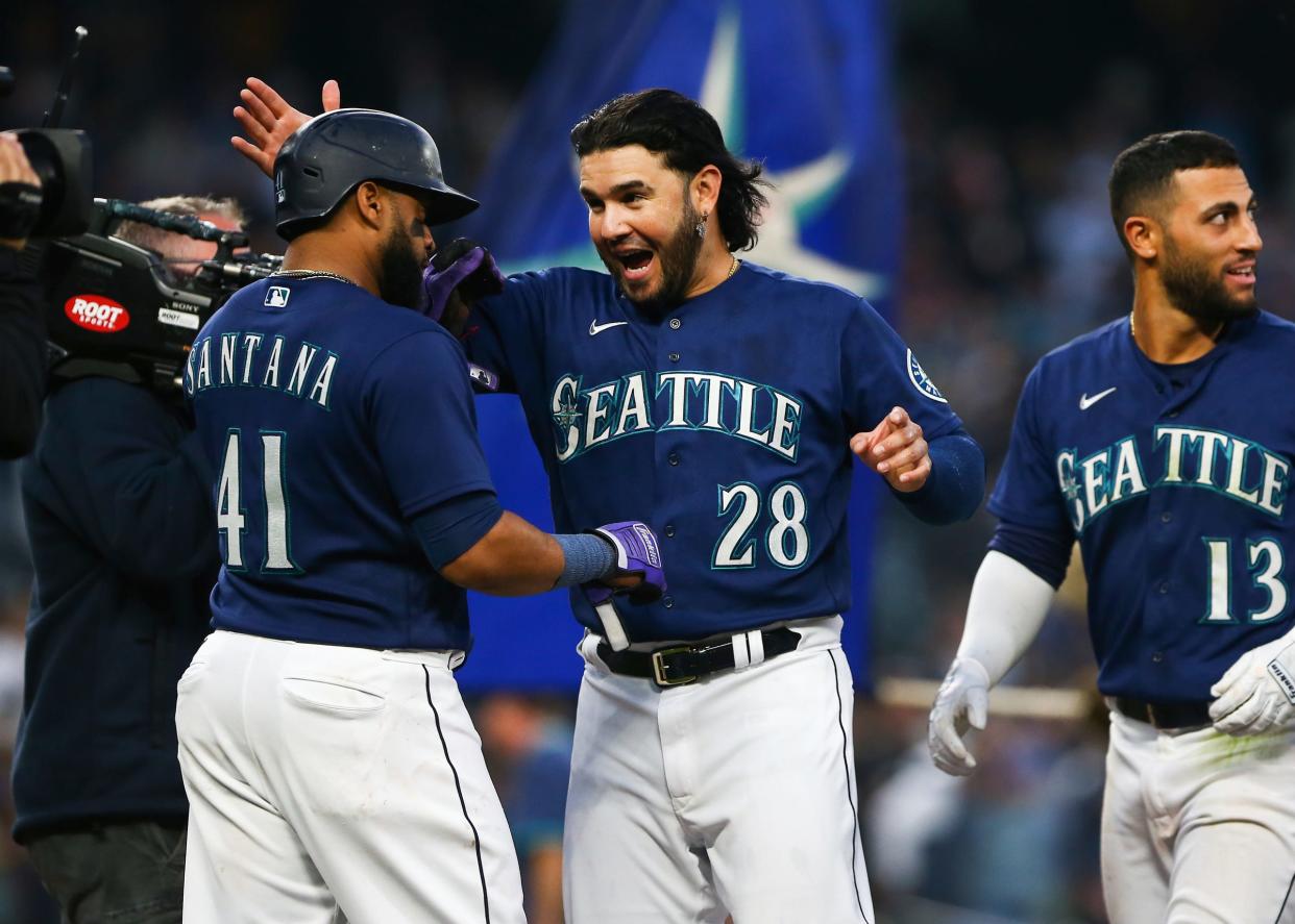 Mariners third baseman Eugenio Suarez, center, greets designated hitter Carlos Santana after Santana scored on a walk-off sacrifice fly from second baseman Abraham Toro (not pictured) to win the game during the 10th inning of the Tigers' 7-6 loss in Game 1 of the doubleheader on Tuesday, Oct. 4, 2022, in Seattle.
