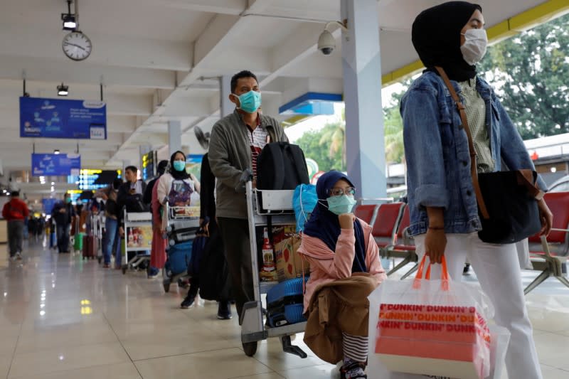 Passengers wearing protective face masks stand in a queue for temperature checking amid the spread of coronavirus disease (COVID-19) at Halim Perdanakusuma airport in Jakarta