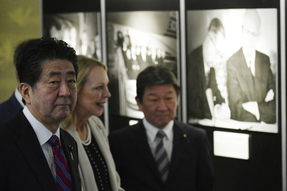 Mary Jean Eisenhower, granddaughter of former U.S. President Dwight D. Eisenhower, center, and Japan's Prime Minister Shinzo Abe, left, watch a photo exposition on the 60th Anniversary commemorative reception of signing of Japan-U.S. Security Treaty at Iikura Guesthouse in Tokyo, Sunday, Jan. 19, 2020. (AP Photo/Eugene Hoshiko, Pool)