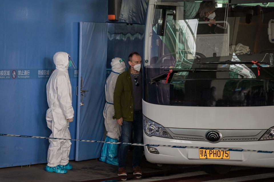 A member of the World Health Organization (WHO) team investigating the origins of the COVID-19 pandemic boards a bus following their arrival at a cordoned-off section of the airport in Wuhan, China, January 14, 2021. / Credit: NICOLAS ASFOURI/AFP/Getty