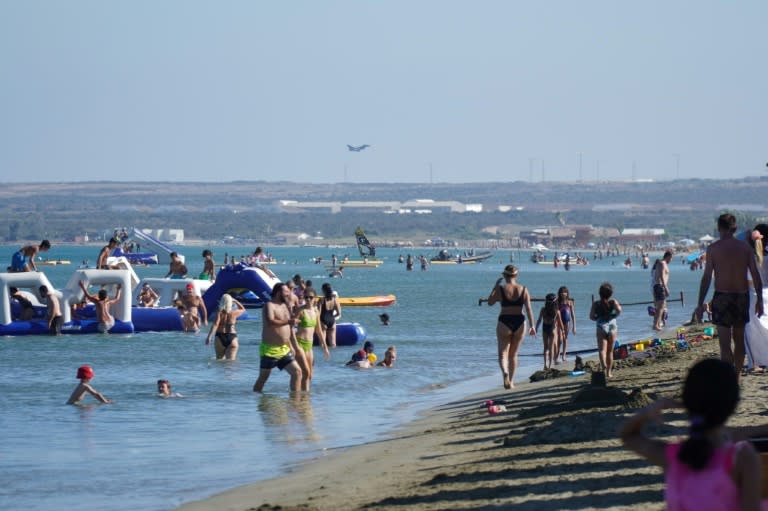 Beachgoers frolic at Lady's Mile in Limassol, Cyprus, as a Eurofighter Typhoon lands at nearby Royal Air Force (RAF) base Akrotiri, on sovereign British territory (Roy ISSA)