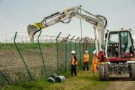 Workers repair a fence securing the Eurotunnel terminal area on October 3, 2015 in Coquelles, near Calais after migrants cut through it and entered the Channel tunnel