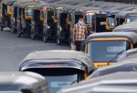 FILE PHOTO: A man wearing a handkerchief as a mask moves past parked autorickshaw during a curfew to limit the spreading of coronavirus disease (COVID-19), in Mumbai