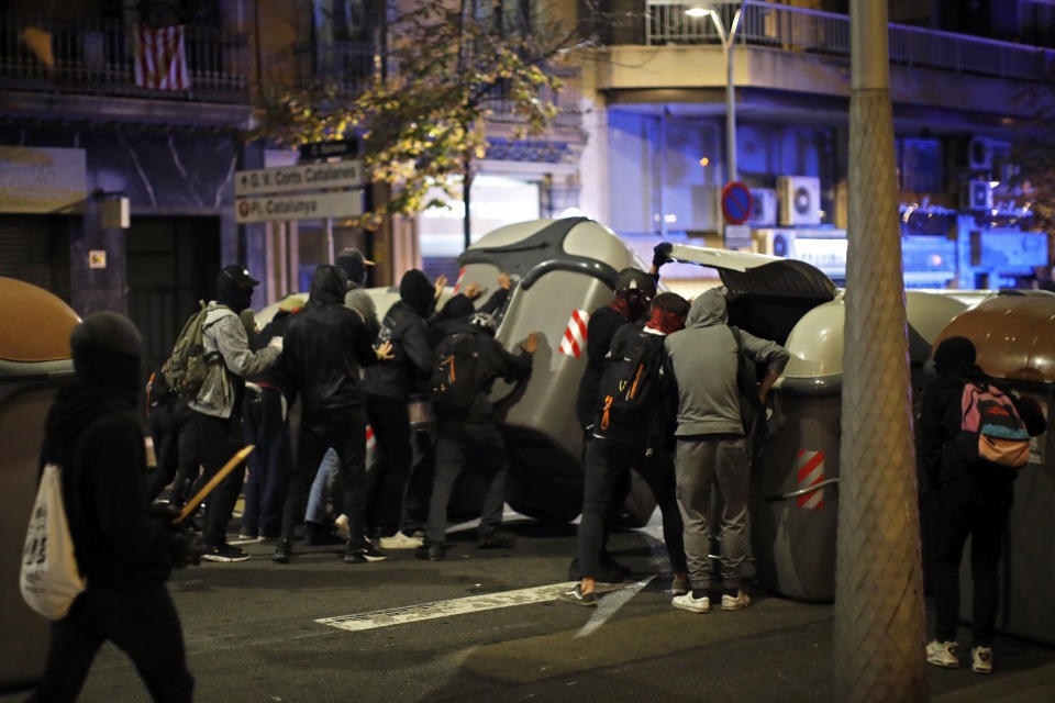 Protestors use garbage containers to build a barricade across a street in Barcelona, Spain, Thursday, Oct. 17, 2019. Catalonia's separatist leader vowed Thursday to hold a new vote to secede from Spain in less than two years as the embattled northeastern region grapples with a wave of violence that has tarnished a movement proud of its peaceful activism. (AP Photo/Emilio Morenatti)