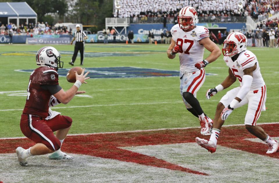 South Carolina quarterback Connor Shaw, left, catches a touchdown pass in the end zone from receiver Bruce Ellington as Wisconsin cornerback Darius Hillary (5) and linebacker Brendan Kelly (97) attempt to defend during the first half of the Capital One Bowl NCAA college football game in Orlando, Fla., Wednesday, Jan. 1, 2014.(AP Photo/John Raoux)