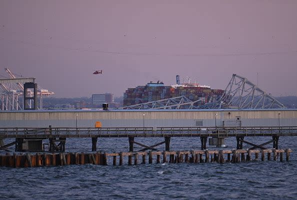 The collapsed steel frame of the Francis Scott Key Bridge and a section of the roadway still upright (L) sit on the water after the bridge collapsed in Baltimore, Maryland, on March 26, 2024. The bridge collapsed after being struck by a container ship, sending multiple vehicles and up to 20 people plunging into the harbor below. 
